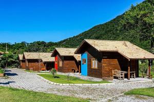 a group of small wooden cabins in front of a mountain at Cabanas aconchegantes. Desfrute da natureza e praia in Florianópolis