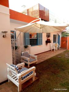 een patio met 2 stoelen en een parasol bij Pouso do Guarani - 200m do mar|wifi|Ar cond in Florianópolis