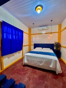 a bedroom with a large bed with blue curtains at Casa de Praia Tutóia in Tutóia