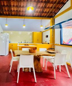 a kitchen with a wooden table and white chairs at Casa de Praia Tutóia in Tutóia