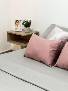 Una cama con almohadas rosas y una foto en una mesa. en Moderna Casa Familiar, en Yopal
