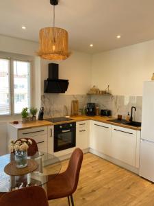 a kitchen with white cabinets and a glass table at Appartement La Maouin 2 pièces in Saint-Laurent-du-Var