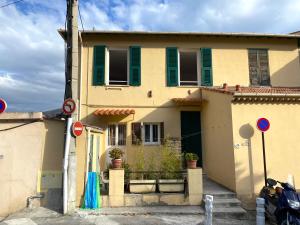 a yellow house with green shutters at Appartement La Maouin 2 pièces in Saint-Laurent-du-Var