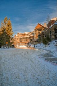 a snow covered street in front of a large house at Mountain Escape sleeps 10 Guests in this 3BD 2BT Top Floor Condo with Mountain View in Canmore