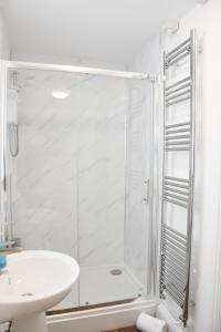 a white bathroom with a shower and a sink at Parkside Apartment in Norwich
