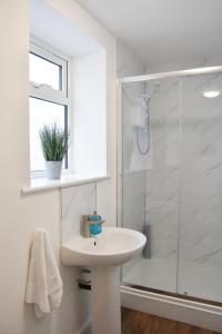 a white bathroom with a shower and a sink at Parkside Apartment in Norwich