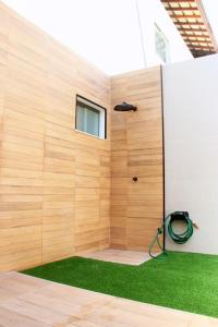a room with a wooden wall and green grass at Exclusivo 2 suites a Beira Mar Imbassaí Privilege in Imbassai