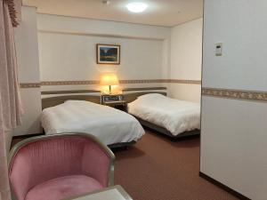 una habitación de hotel con 2 camas y una silla en Hotel Alpha-One Tokuyama, en Shunan