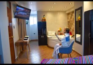 una mujer sentada en una silla viendo una tele en una habitación en MELTHON URBANS, en Ayacucho