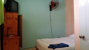 ein kleines Schlafzimmer mit einem Bett und einem TV sowie ein Zimmer in der Unterkunft Lucy Rooms in Juan Dolio