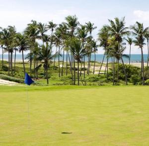 widok na pole golfowe z palmami i ocean w obiekcie Manhattan Beach Riviera w mieście Aquiraz