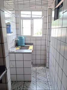 ein weiß gefliestes Bad mit einem Waschbecken und einem Fenster in der Unterkunft Apartamento grande Vitória in Vitória