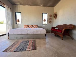 a bedroom with a bed and a chair and a rug at habitación en Casa Palma y Coco in Playa Agua Blanca