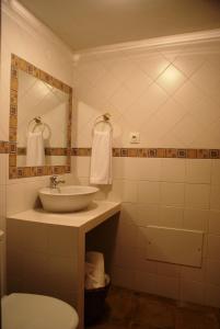 a bathroom with a sink and a toilet and a mirror at Encosta do Castelo in Portel