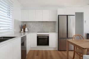 een keuken met witte kasten en een roestvrijstalen koelkast bij No 2 Luana in Nelson Bay