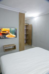1 dormitorio con 1 cama y TV en la pared en Plot 100, en Lagos