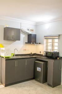 eine Küche mit schwarzen Schränken und einer Arbeitsplatte in der Unterkunft Plot 100 in Lagos