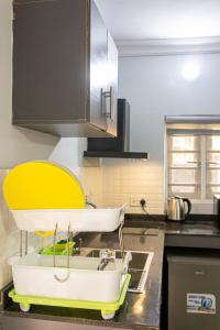 a kitchen sink with a yellow and white dishrack at Plot 100 in Lagos