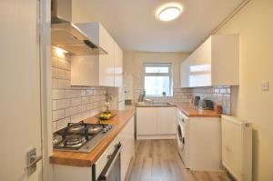 a kitchen with white cabinets and a stove top oven at Curve Apartments in London