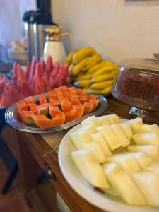 a table topped with plates of cheese and fruit at Casario 1915 Pousada in Morretes