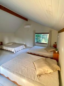 Duas camas num quarto com uma janela em Chalé Oxente em Corumbau-BA em Corumbau