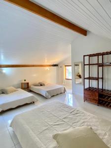 Duas camas num quarto com paredes brancas em Chalé Oxente em Corumbau-BA em Corumbau