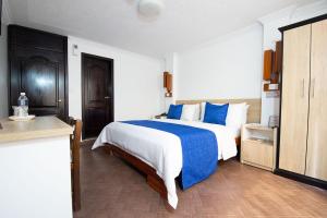 a bedroom with a large bed with blue and white sheets at Hotel Plaza Victoria in Ibarra