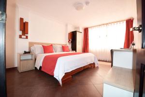 1 dormitorio con 1 cama grande con almohadas rojas en Hotel Plaza Victoria, en Ibarra