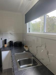 cocina con fregadero y ventana en Batemans Bay North Bush Cottages, en Benandarah