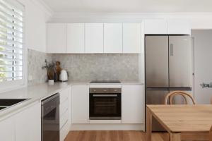 a kitchen with white appliances and a wooden table at No 3 Luana in Nelson Bay