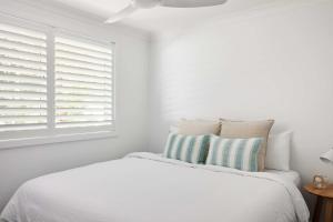 a white bedroom with a bed and a window at No 3 Luana in Nelson Bay