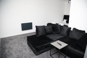 um sofá preto numa sala de estar com uma mesa em The Hideaway em Birmingham