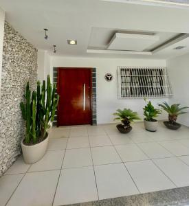 um corredor com vasos de plantas e uma porta vermelha em Hospedagem Caminho das Praias em Niterói