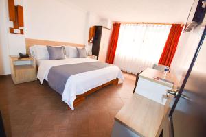 a hotel room with a bed and a window at Hotel Plaza Victoria in Ibarra