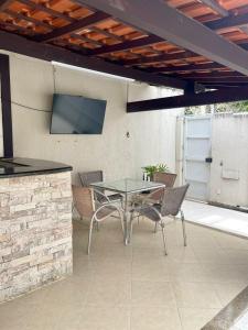 patio con mesa, sillas y TV en Hospedagem Caminho das Praias en Niterói