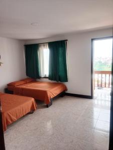 a room with two beds and a window with green curtains at La iguana café y más in Pereira