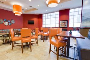 une salle à manger avec des chaises et des tables orange dans l'établissement Drury Inn & Suites Greenville, à Greenville