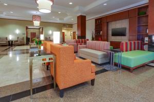 Drury Inn & Suites St. Louis Forest Park في سانت لويس: لوبي مع غرفة انتظار مع كراسي وتلفزيون