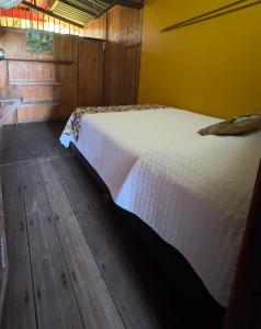 a bedroom with a white bed with a wooden floor at Posada Turística Rocas De Cabo Marzo in Bahía Solano