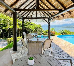 un patio con tavoli, sedie e piscina di SUNSET PORTO BELO Locaçoes a Porto Belo