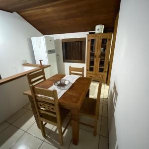 La cuisine est équipée d'une table et de chaises en bois ainsi que d'un réfrigérateur. dans l'établissement Casa Beira Mar, Paraty-RJ, à Parati