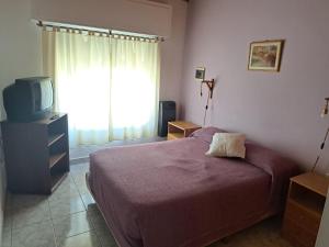 1 dormitorio con 1 cama, TV y ventana en LAS HERMANAS en Tandil