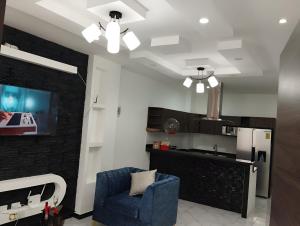 a living room with a blue chair and a kitchen at Casa cerca del Terminal de SANTO DOMINGO in Santo Domingo de los Colorados +5 photos