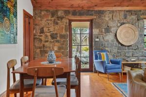 a dining room with a table and chairs and a stone wall at Breakfast Creek Cottage in Port Fairy