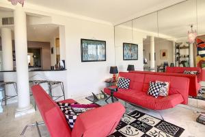 a living room with a red couch and chairs at Superb 2 bedroom apartment with sea view on the Croisette in Cannes