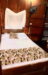 Bett in einem Holzzimmer mit einer Tagesdecke mit Fisch darauf in der Unterkunft Posada Turística Rocas De Cabo Marzo in Bahía Solano