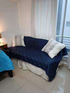 a bed with a blue comforter and pillows in a room at Monoambiente en Montserrat "departamentosji" in Buenos Aires