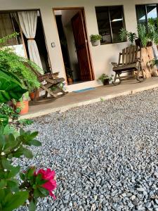 a house with a gravel patio with a bench and a flower at Verde Amanecer in Bijagua