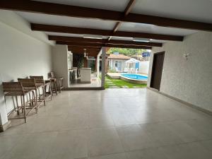una sala de estar vacía con un patio con sillas y una mesa. en Casa da Jana com piscina en Porto Seguro