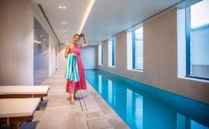 Holiday Inn & Suites Geelong, an IHG Hotel في جيلونج: امرأة ترتدي ثوب تقف بجوار حمام السباحة